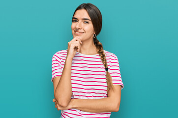 Young hispanic woman wearing casual clothes looking confident at the camera with smile with crossed arms and hand raised on chin. thinking positive.