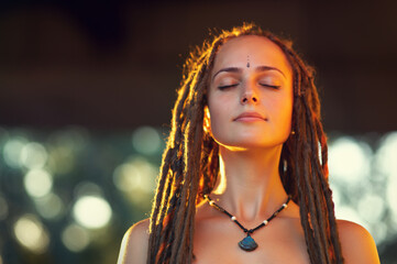 Close-up of a young woman in dreadlocks practicing yoga on the street