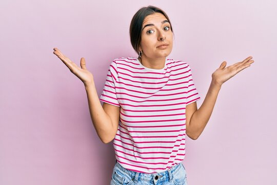 Young hispanic woman wearing casual clothes clueless and confused with open arms, no idea and doubtful face.