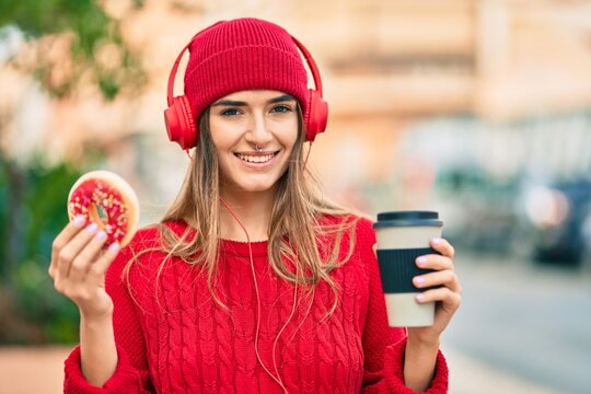 Young hispanic woman having breakfast using headphones at the city.