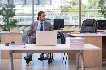 Young male employee in wheel-chair working in the office