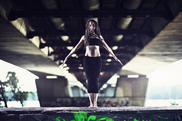 Obraz premium Close-up of a young woman in dreadlocks practicing yoga on the street