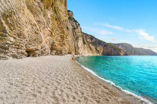 The turquoise aqua green clear water along the hidden cove of sandy Paradise Beach, also known as Chomi Beach in the Aegean Sea off Corfu, Greece.