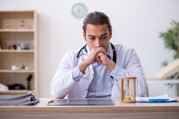 Young male doctor in time management concept