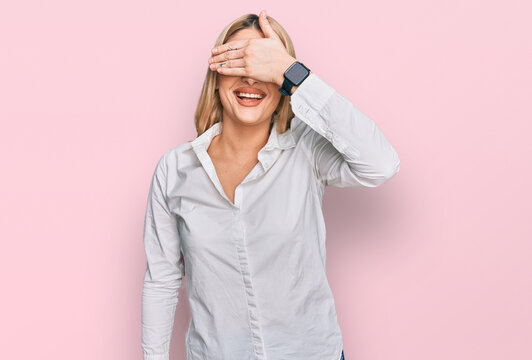 Young caucasian woman wearing casual clothes smiling and laughing with hand on face covering eyes for surprise. blind concept.