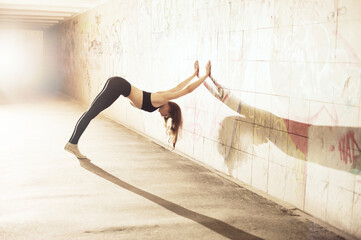 Young caucasian woman practicing yoga on the city streets.