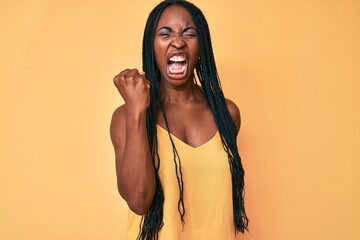 African american woman with braids wearing casual clothes angry and mad raising fist frustrated and...
