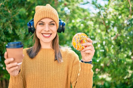 Young blonde woman using headphones and having breakfast at the park.