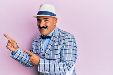 Mature middle east man with mustache wearing vintage and elegant fashion style smiling and looking at the camera pointing with two hands and fingers to the side.
