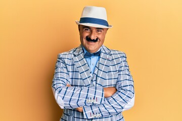 Mature middle east man with mustache wearing vintage and elegant fashion style happy face smiling with crossed arms looking at the camera. positive person.