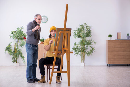 Young man taking lesson from old painter
