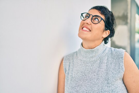 Young plus size woman smiling happy leaning on the wall at the city.