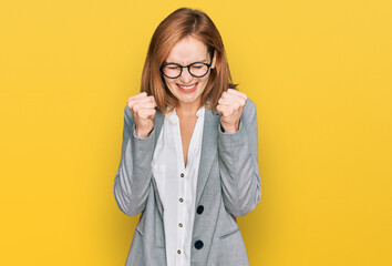 Young caucasian woman wearing business style and glasses excited for success with arms raised and eyes closed celebrating victory smiling. winner concept.