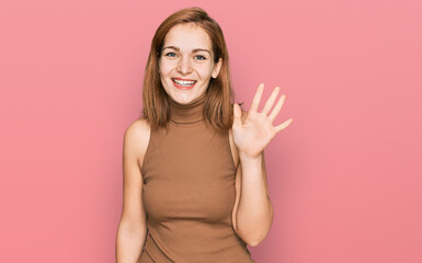 Young caucasian woman wearing casual clothes showing and pointing up with fingers number five while smiling confident and happy.