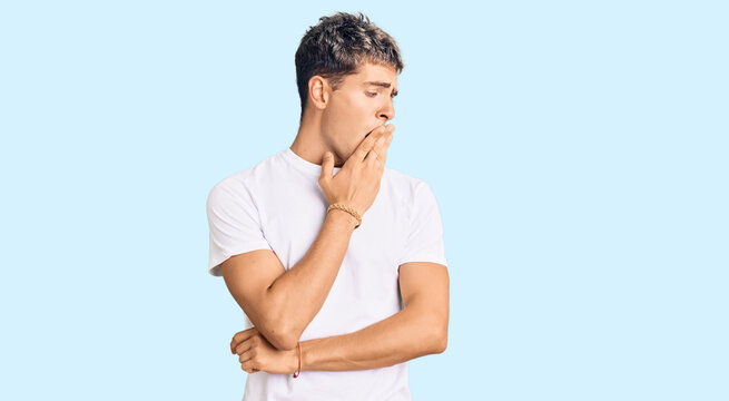 Young handsome man wearing casual white tshirt bored yawning tired covering mouth with hand. restless and sleepiness.