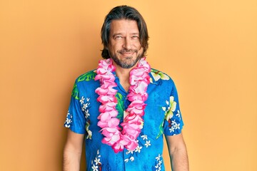 Middle age handsome man wearing summer shirt and hawaiian lei with a happy and cool smile on face....
