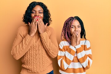 Beautiful african american mother and daughter wearing wool winter sweater laughing and embarrassed...