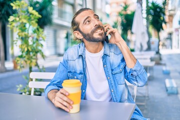 Young middle eastern man talking on the smartphone and drinking coffee at coffee shop.