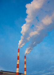 factory chimneys emit thick smoke against the blue sky. environmental pollution and ecology concept.