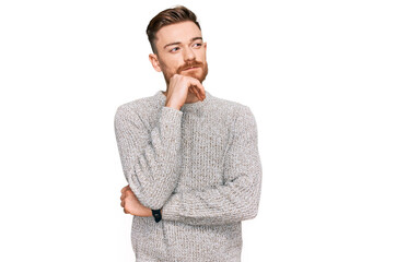 Young redhead man wearing casual winter sweater with hand on chin thinking about question, pensive...
