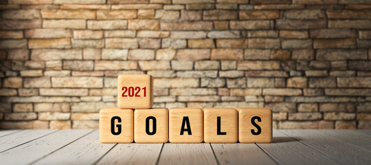 Fototapeta na wymiar wooden cubes with the message GOALS 2021 on wooden surface in front of a brick wall