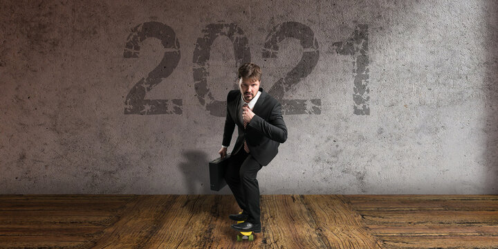 businessman on a skateboard in front of a concrete wall with message 2021