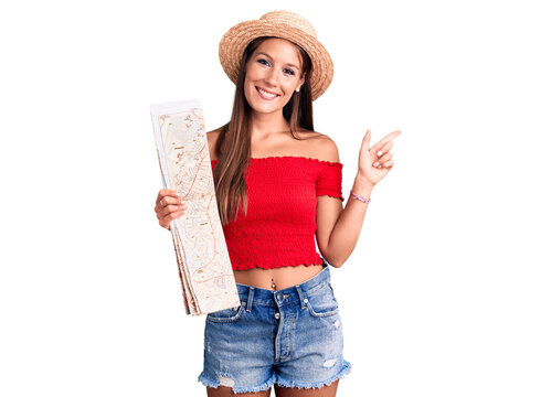 Young beautiful hispanic woman wearing summer hat holding city map smiling happy pointing with hand and finger to the side