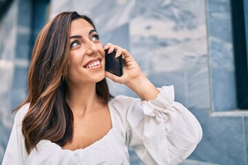 Young hispanic woman smiling happy talking on the smartphone at the city.
