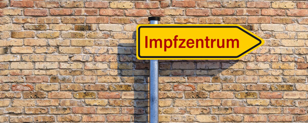 Fototapeta premium street sign with German message for VACCINATION CENTER in front of a brick wall background