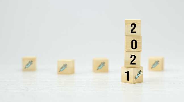 cubes with number 2021 and vaccination symbol on wooden  background