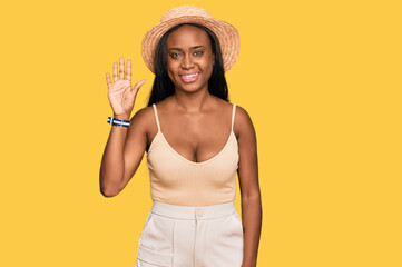 Young black woman wearing summer hat showing and pointing up with fingers number five while smiling confident and happy.