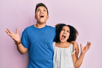 Obraz premium Young hispanic family of brother and sister wearing casual clothes together crazy and mad shouting and yelling with aggressive expression and arms raised. frustration concept.
