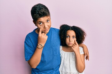 Young hispanic family of brother and sister wearing casual clothes together pointing to the eye watching you gesture, suspicious expression