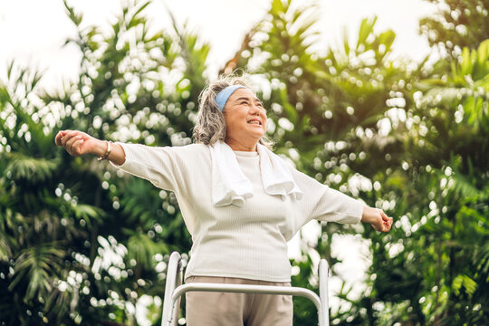 Portrait of happy senior old adult elderly asia women smiling standing and stretch her arms relax and enjoy with nature feeling breath fresh clean air in green park.Healthcare