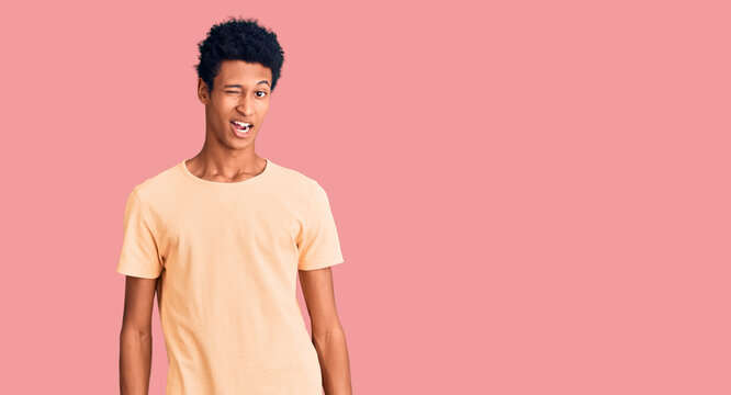 Young african american man wearing casual clothes winking looking at the camera with sexy expression, cheerful and happy face.