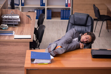 Young male employee sleeping at workplace