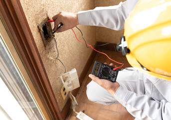 住宅リフォーム　解体現場 ACコンセントの通電を調査するビジネスマン　