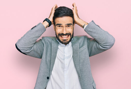 Young hispanic man wearing business clothes crazy and scared with hands on head, afraid and surprised of shock with open mouth