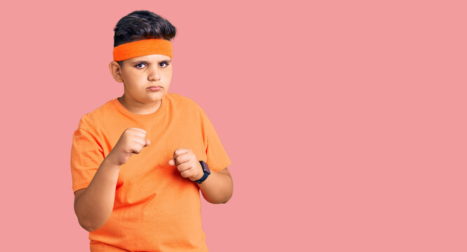Little boy kid wearing sportswear ready to fight with fist defense gesture, angry and upset face, afraid of problem