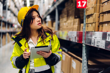 Portrait of smiling asian engineer in helmets woman order details on tablet computer for checking goods and supplies on shelves with goods background in warehouse.logistic and business export