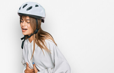 Teenager caucasian girl wearing bike helmet with hand on stomach because nausea, painful disease feeling unwell. ache concept.