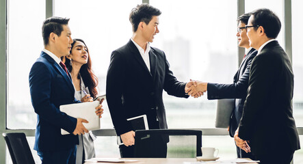 Image two asian business partners successful handshake together in front of group teamwork casual business clapping hands winning success agreement in modern office