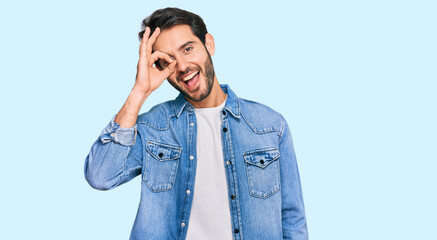 Fototapeta premium Young hispanic man wearing casual clothes doing ok gesture with hand smiling, eye looking through fingers with happy face.