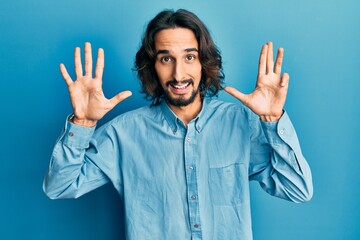 Young hispanic man wearing casual clothes showing and pointing up with fingers number nine while smiling confident and happy.