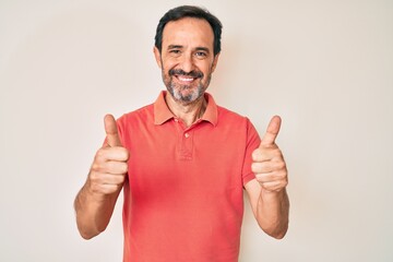 Middle age hispanic man wearing casual clothes success sign doing positive gesture with hand,...