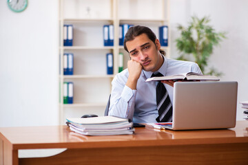 Young male student employee reading book at workplace