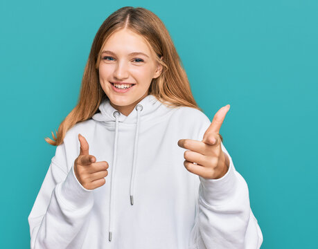 Beautiful young caucasian girl wearing casual sweatshirt pointing fingers to camera with happy and funny face. good energy and vibes.