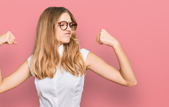 Beautiful young caucasian girl wearing casual clothes and glasses showing arms muscles smiling proud. fitness concept.