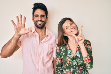 Beautiful young couple of boyfriend and girlfriend together showing and pointing up with fingers...