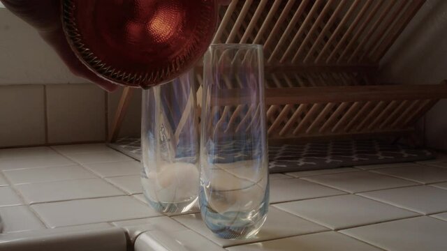 Two Stemless Champagne Flutes Being Filled With Sparkling Rosé